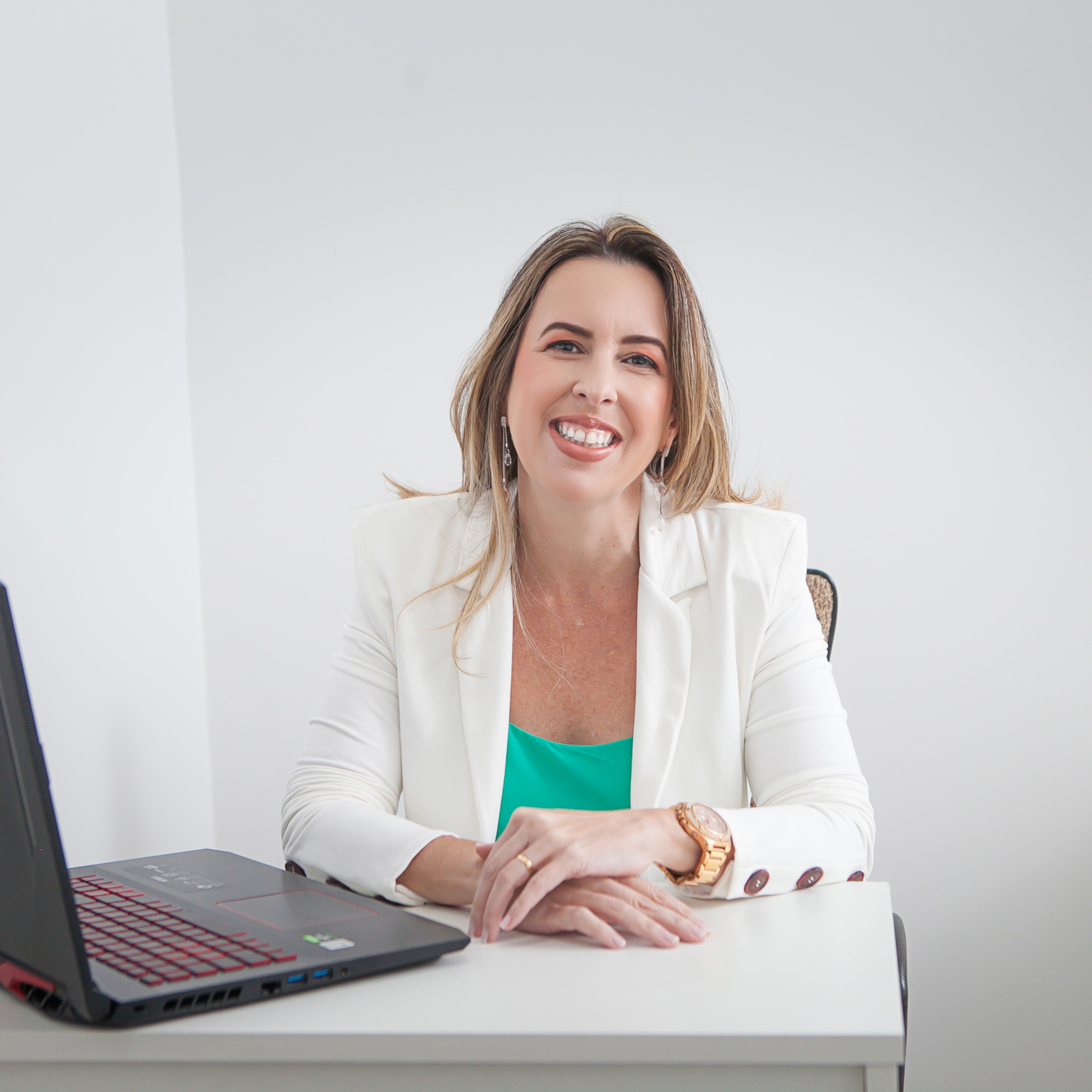 Foto da Dra Carla Galati em sua mesa ao lado de um notebook